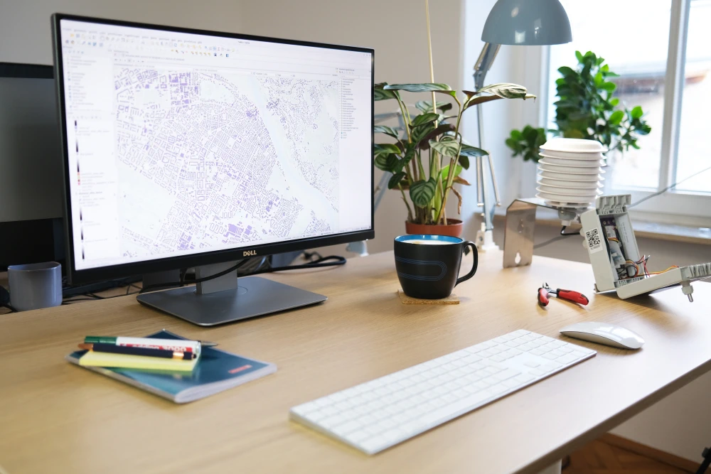 A tidy workstation with a sensor, writing utensils, coffee and a monitor.