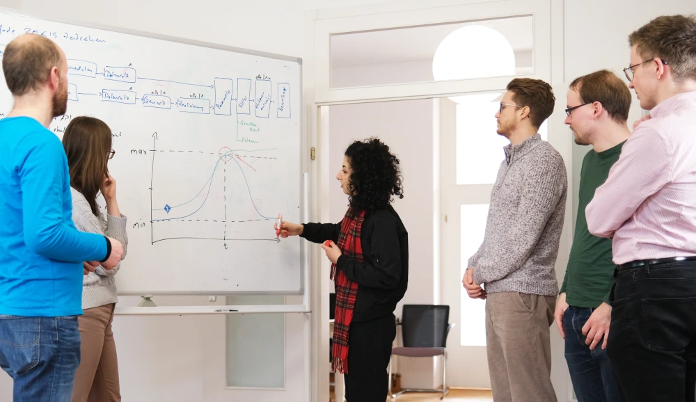 Employees discuss together on a whiteboard.