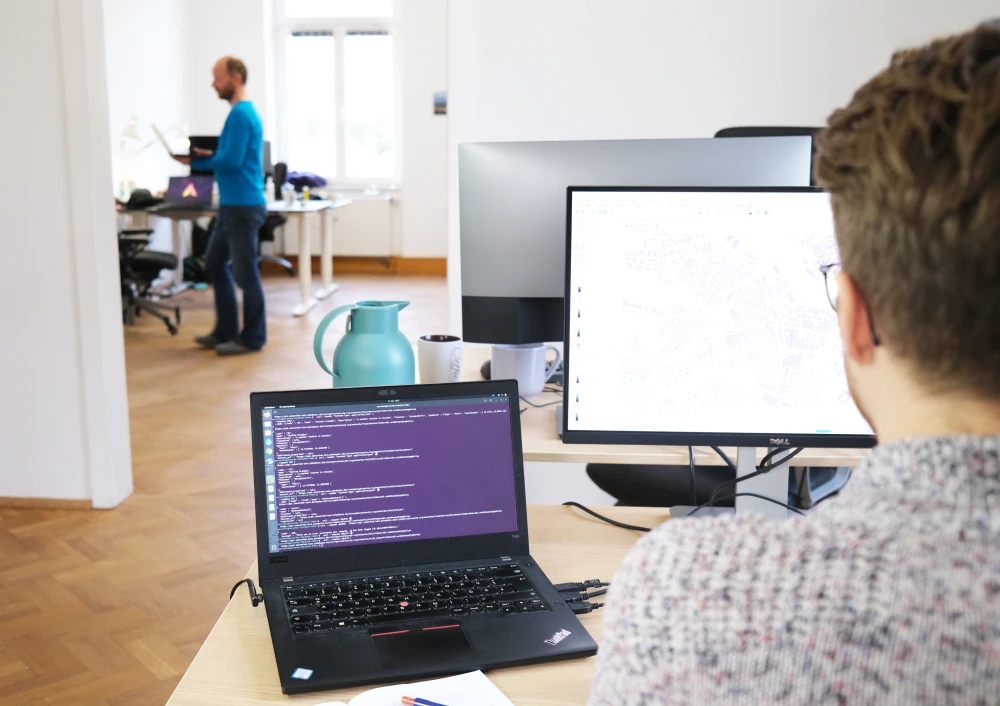 Looking over the shoulder of a employee into a bright office space. 