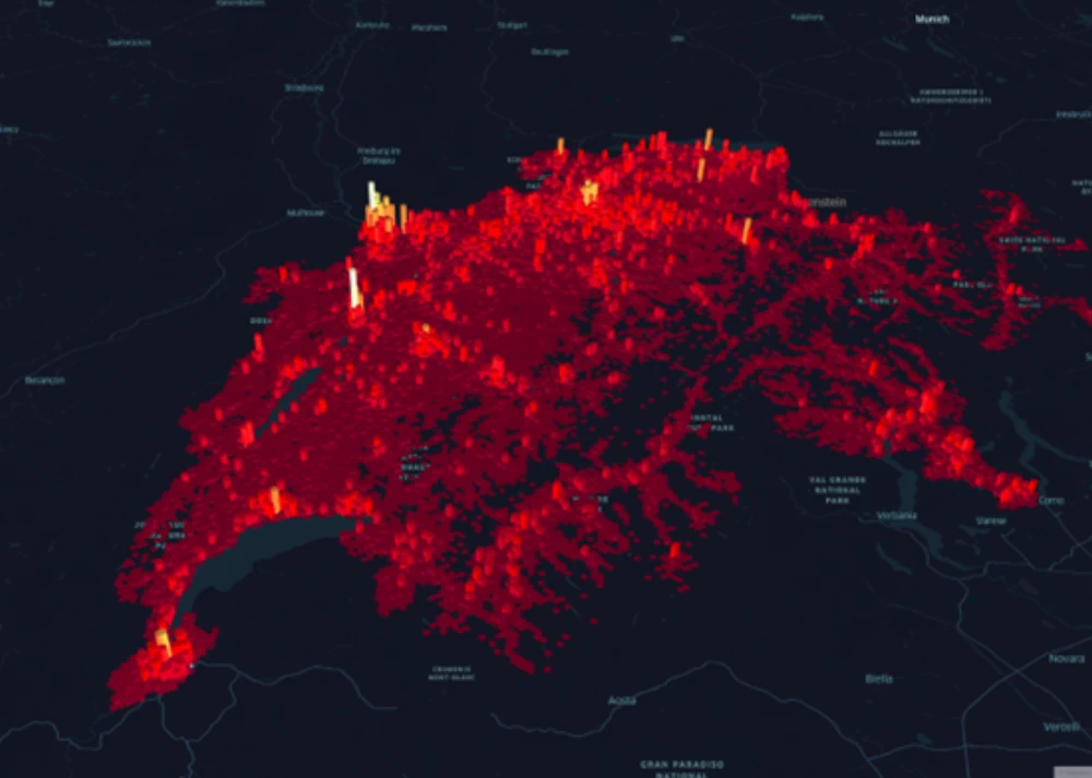 Das Bild zeigt eine Heatmap der Schweiz, die die Bevölkerungsdichte bzw. Aktivitätsniveaus darstellt, wobei intensive rote und gelbe Bereiche höhere Konzentrationen anzeigen. Städtische Gebiete und Großstädte, wo viele Menschen auf engem Raum leben und arbeiten, treten deutlich hervor.